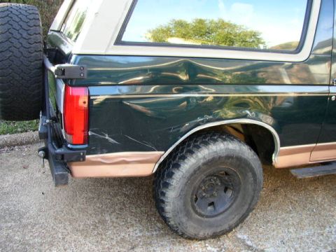 1995 Ford Bronco - Rear view of a damaged 1995 Ford Bronco showing extensive body damage on the quarter panel.