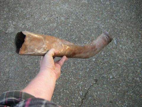 1995 Ford Bronco - A person holds a damaged exhaust pipe against a concrete surface.