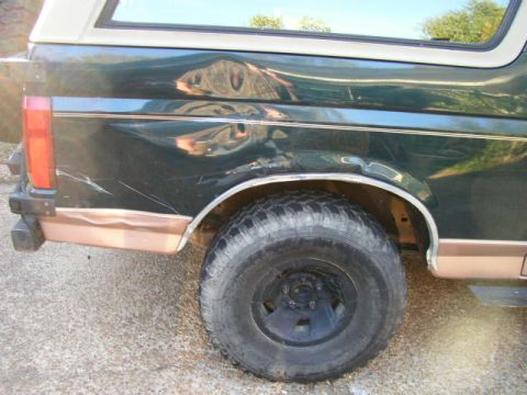 1995 Ford Bronco - This Ford Bronco shows significant body damage on its rear quarter panel and lower trim.