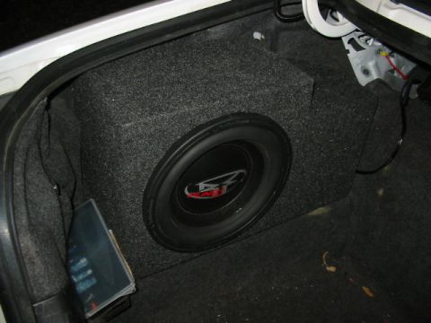 1997 Ford Crown Victoria - A large subwoofer is installed in the trunk of a vehicle, with visible wiring and carpeted lining.