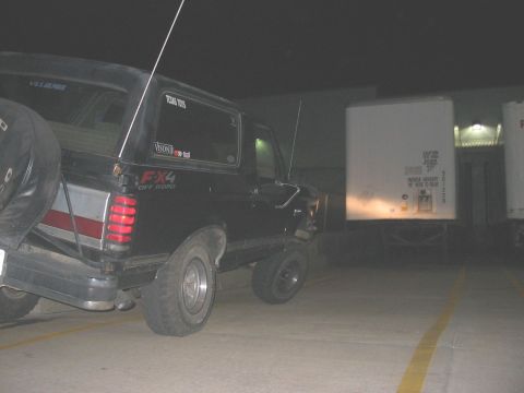 1988 Ford Bronco - Black Ford Bronco with FX4 Off Road decal and a flat rear tire parked at night.