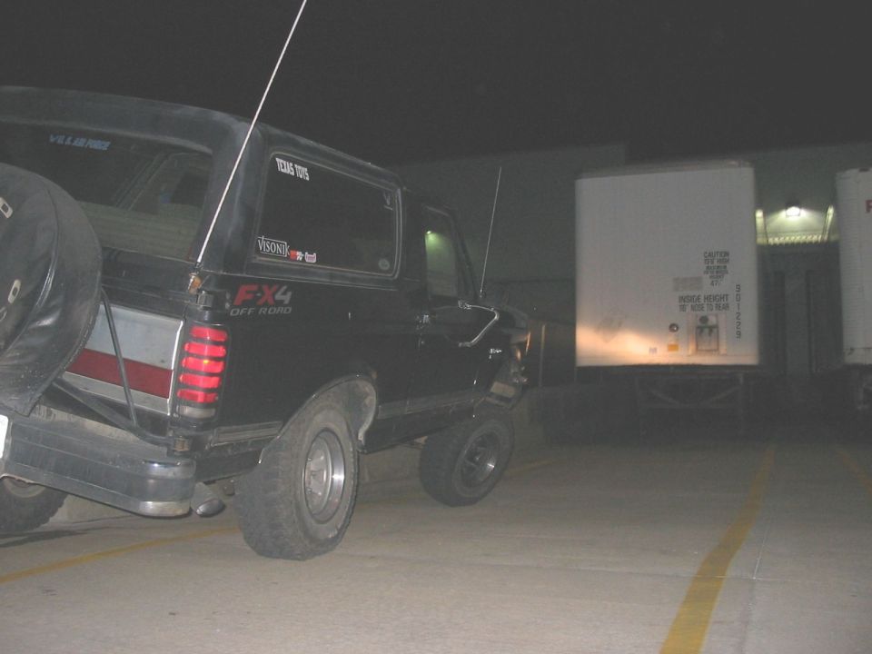 Black Ford Bronco with FX4 Off Road decal, spare tire on rear, flat rear tire, red and white stripe on tailgate