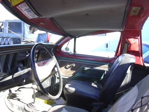 1978 Ford Bronco - The interior of an older vehicle is shown, with a sticker on the visor and other vehicles visible through the windows.