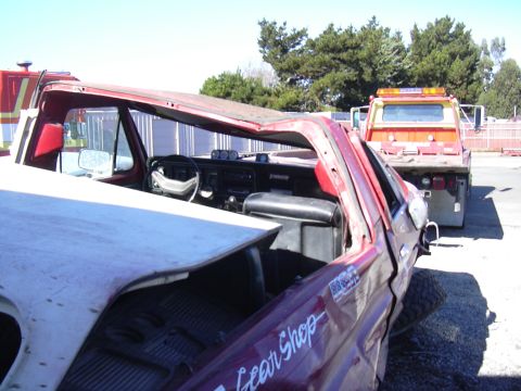 1978 Ford Bronco - A wrecked red pickup truck interior is visible, with a tow truck in the background.
