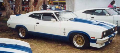 1973 Ford Ranchero - A white and blue Ford Falcon coupe is displayed outdoors, with another vehicle partially visible.