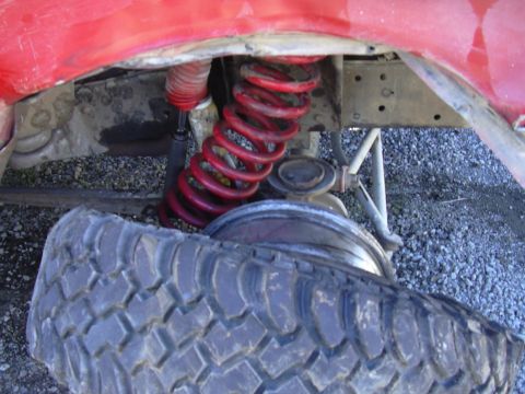 1978 Ford Bronco - Close-up of a vehicle's undercarriage, showing a red coil spring and a detached tire.