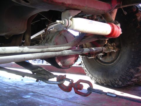 1978 Ford Bronco - A close-up view of a vehicle's undercarriage, focusing on the suspension and a tow strap. The "SUPERMOTORS" watermark is visible.