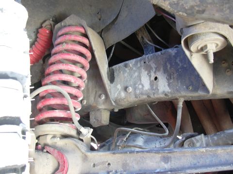 1978 Ford Bronco - Close-up view of the suspension system of a 1978 Ford Bronco, showing red coil springs and shock absorbers.