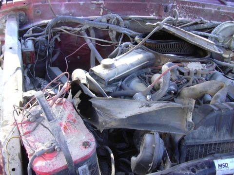1978 Ford Bronco - Engine bay of a 1978 Ford Bronco with a damaged battery and extensive wiring.