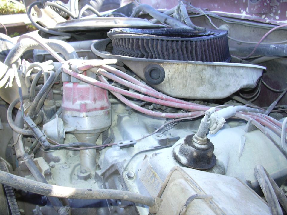 Engine bay of a 1978 Ford Bronco showing distributor cap, spark plug wires, and air filter