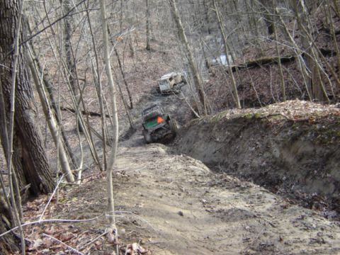 1992 Ford Bronco - Off-road vehicles tackle a challenging dirt path in a wooded area.