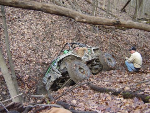 1992 Ford Bronco - Off-road buggy stuck in mud on a wooded hillside, with a person observing the situation.