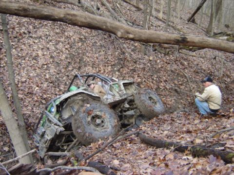 1992 Ford Bronco - A person watches an off-road buggy that has gotten stuck on a steep, wooded slope covered in leaves.