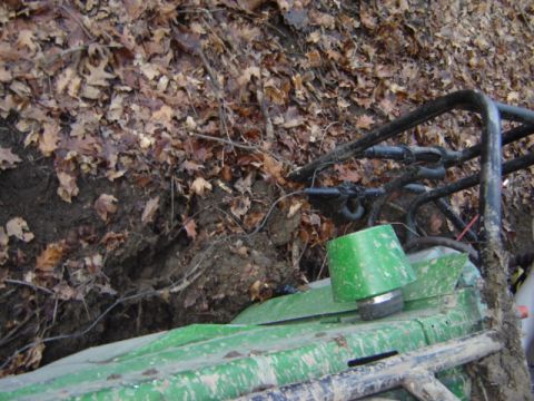 1992 Ford Bronco - A green off-road vehicle navigates a muddy, leaf-covered embankment.