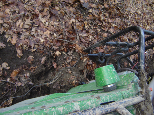 Green off-road vehicle with roll cage in muddy terrain