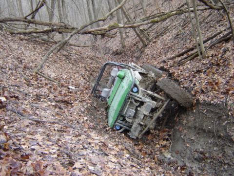 1992 Ford Bronco - An off-road vehicle has gone off the path and is resting on its side in a wooded area.