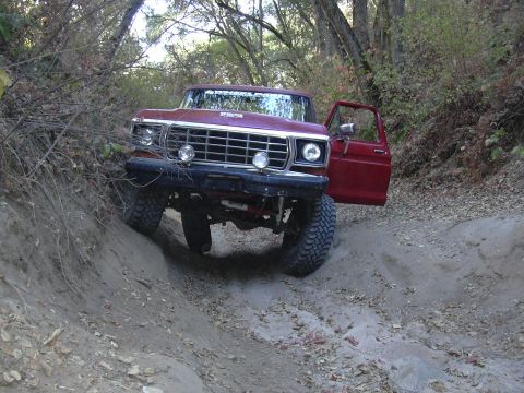 1978 Ford Bronco - A red 1979 Ford F-Series truck navigates a steep dirt trail with its driver's door ajar.