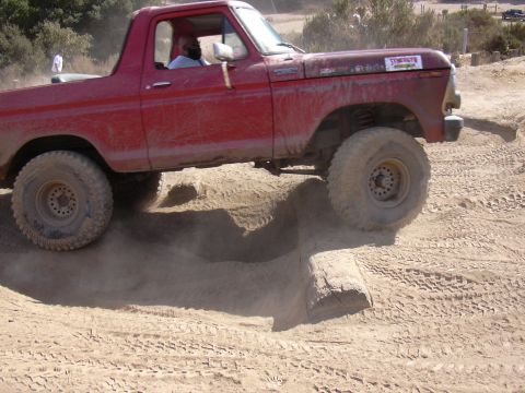 1978 Ford Bronco - This red 1978 Ford Bronco navigates a challenging obstacle on a dusty off-road course.