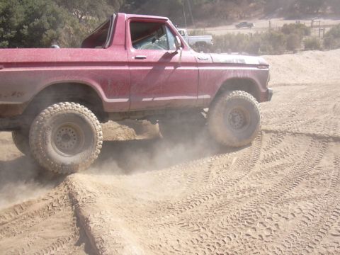 1978 Ford Bronco - This red 1978 Ford Bronco navigates a challenging dirt track, with another vehicle visible in the background.