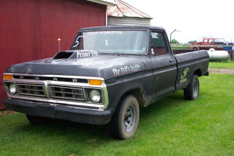 1977 Ford F-150 - This modified 1977 Ford F-150 pickup features a prominent hood scoop and custom graphics, including 'Primer Evil' and 'The Devil's Inside'.