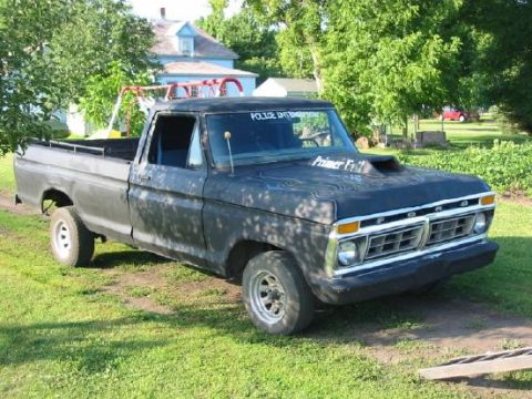 1977 Ford F-150 - This 1977 Ford F-150 pickup truck features a custom hood with flame graphics and a prominent "Ford" grille.