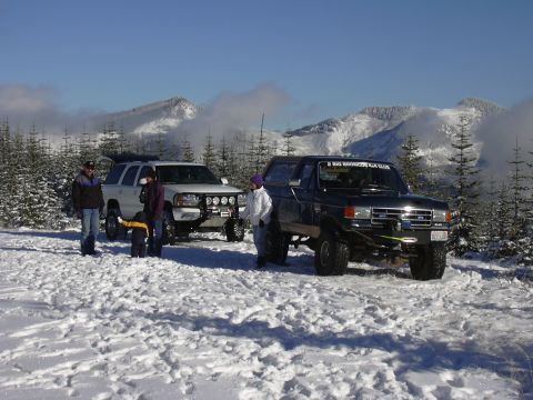 1991 Ford Bronco - Two SUVs are parked in a snowy mountain landscape, with people standing nearby.