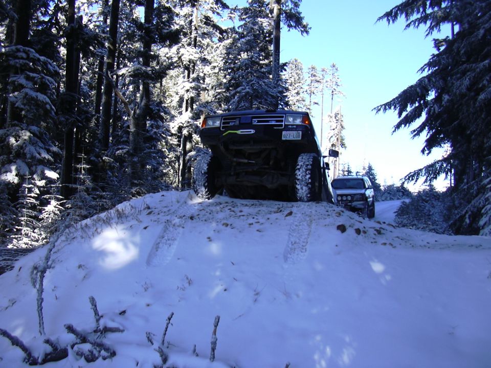 Dark 1991 Ford Bronco climbing snowy hill, front view