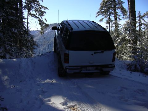 1991 Ford Bronco - SUV navigates a snowy path through a winter forest landscape.