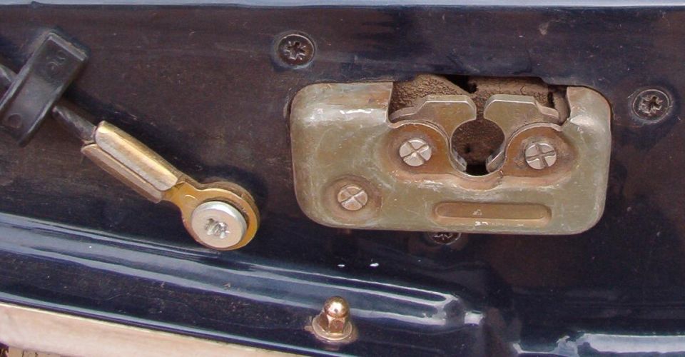 Tailgate or door latch mechanism with linkage rod on a dark vehicle panel