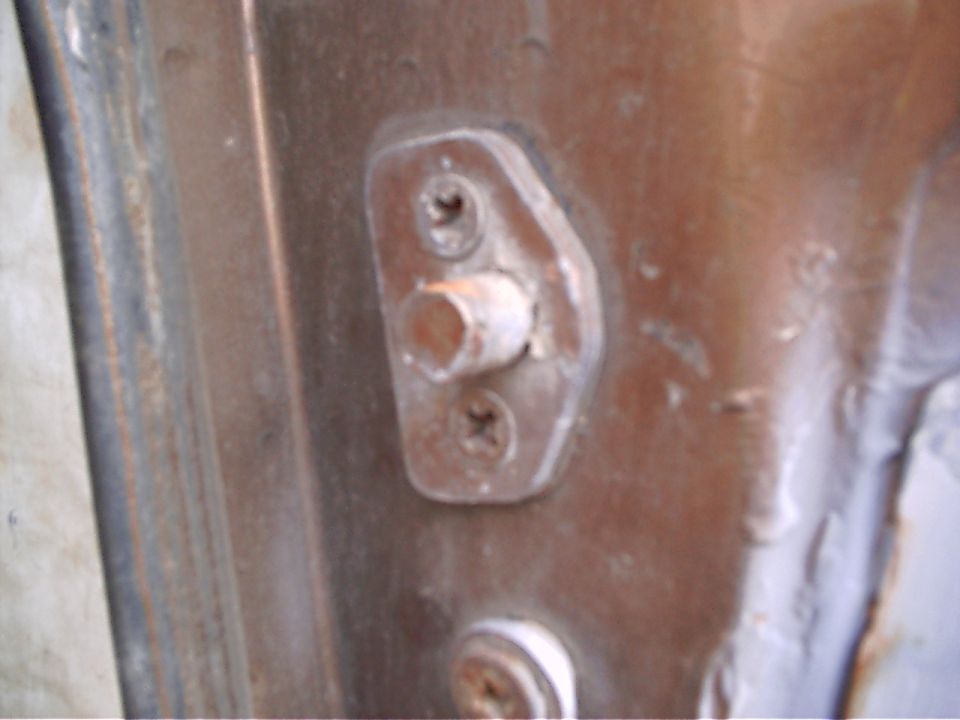 Door striker plate bolted to brown painted body pillar