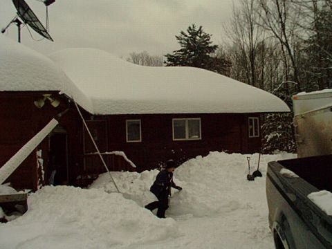 2000 Ford Mustang - A person walks through deep snow near a house, with a truck and trailer visible.