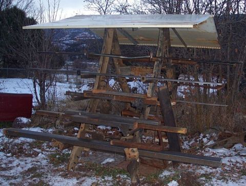 1990 Ford Bronco - A makeshift rack holds various metal stock and lumber outdoors, with a snowy landscape in the background.