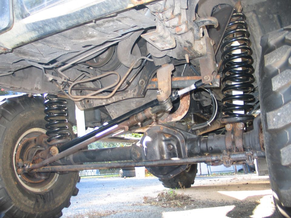 Underside of lifted 4x4 front axle with coil springs, differential and steering linkage