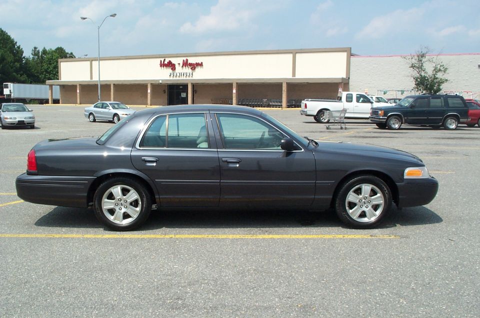 Dark gray Ford Crown Victoria parked in front of strip mall storefront