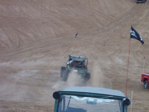 2000 Ford F-450 - An off-road buggy navigates a sandy terrain, leaving a trail of dust in its wake.