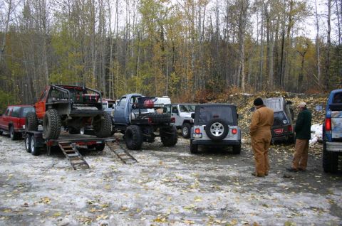 2003 Jeep TJ - Several off-road vehicles are parked in a wooded area with snow on the ground, including a silver Jeep TJ.