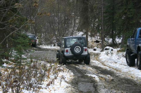 2003 Jeep TJ - Two off-road vehicles navigate a challenging trail with mud and snow.