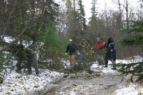 2003 Jeep TJ - People gather in a snow-dusted forest, surrounded by trees and debris.