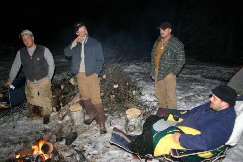 2003 Jeep TJ - Men are gathered around a campfire in a snowy, wooded area at night.