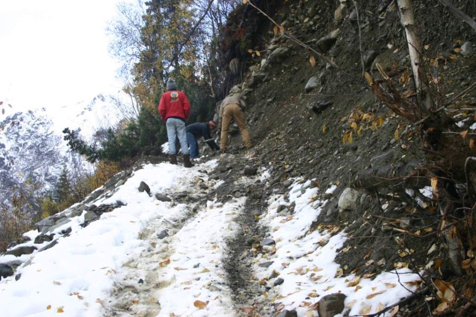 People on a snowy mountain trail with trees and rocks