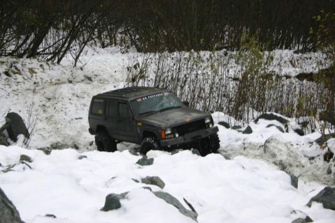 2003 Jeep TJ - A Jeep Cherokee XJ navigates a snowy, rocky terrain, demonstrating its off-road capabilities.