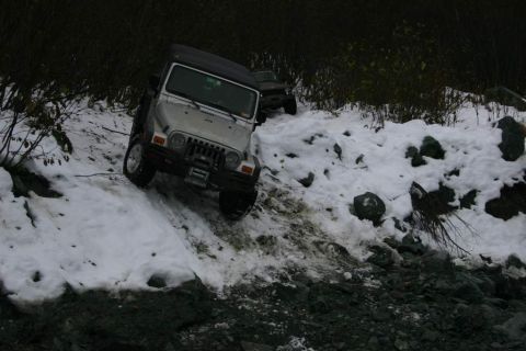 2003 Jeep TJ - Two Jeeps navigate a snowy, rocky trail in an off-road setting.
