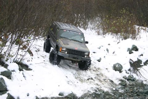 2003 Jeep TJ - A Jeep Cherokee XJ navigates a challenging snowy and rocky terrain.