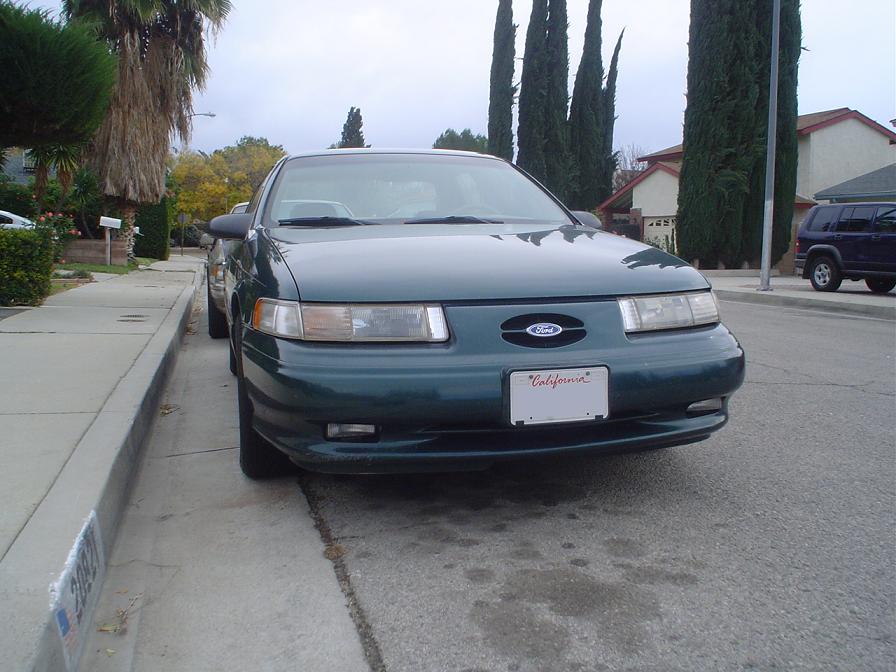 Dark green Ford Taurus sedan front view parked at a suburban California curb