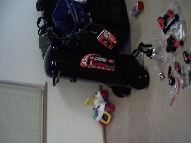 Black air compressor with red and white labels, various tools scattered around