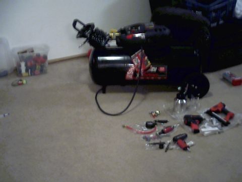 1987 Ford Bronco - Air compressor and a collection of pneumatic tools are laid out on the floor.