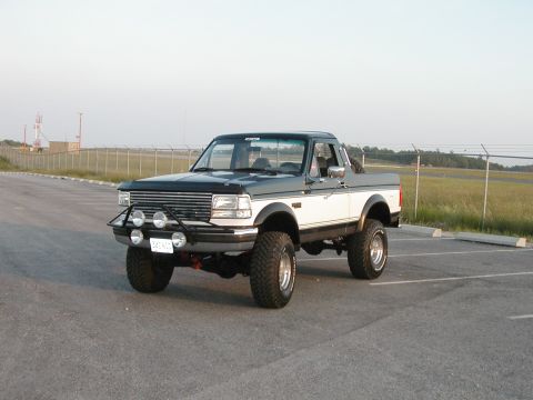 1994 Ford Bronco - This lifted Ford F-Series pickup has a two-tone paint scheme and auxiliary lights on the front bumper.