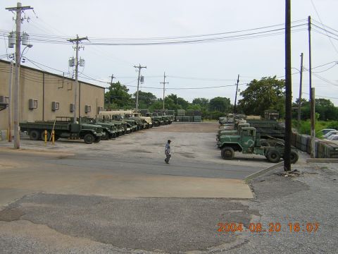 1984 Chevrolet Blazer - A collection of military trucks are parked in an outdoor lot next to a building.