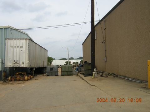 1984 Chevrolet Blazer - An outdoor industrial scene with a large trailer and various containers under a cloudy sky.