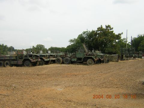 1984 Chevrolet Blazer - Multiple military trucks are parked in an outdoor lot under an overcast sky.